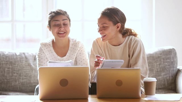 Two happy diverse girls students friends studying together at home