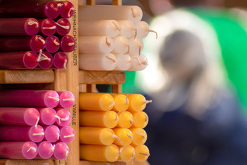 Bunte Duftkerzen und farbenfrohe Kerzen auf einem Marktstand eines Weihnachtsmarkt oder Christkindlemarkt bereitet eine duftende Adventszeit mit Adventskranz basteln und Atmosphäre vor