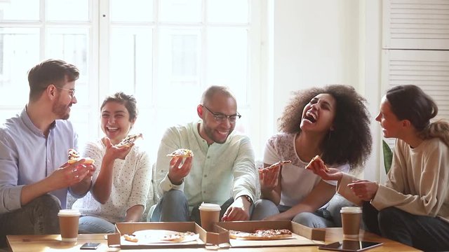 Happy multiracial young people group laughing eating pizza indoors