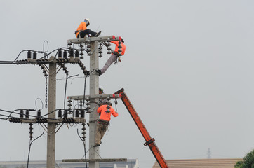 Electricians are climbing on electric poles to install and repair power lines.