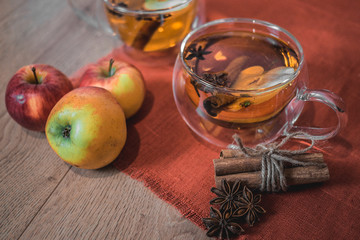 Apple Cider Drink, Juice, Punch, Tea with Spices, Cinnamon sticks, star anise and fresh Apples on a wooden background. Hot drink for Autumn and Winter evenings. Close up. Seasonal mulled drink.