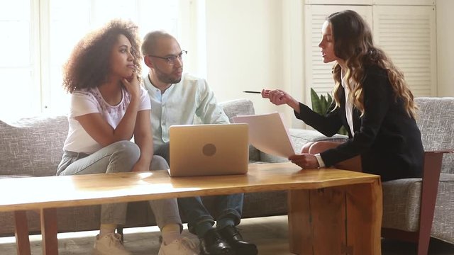Female realtor broker consulting young african couple tenants in apartment