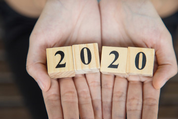 Wooden block number 2 0 2 0 on woman hand.