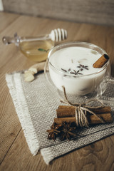 Glass cup of traditional indian masala chai tea. Indian masala chai tea - spiced tea with milk on rustic wooden background, selective focus, copy space. Close up.