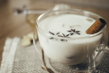 Glass cup of traditional indian masala chai tea. Indian masala chai tea - spiced tea with milk on rustic wooden background, selective focus, copy space. Close up.