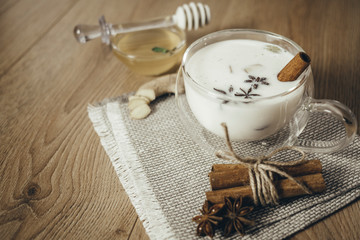 Glass cup of traditional indian masala chai tea. Indian masala chai tea - spiced tea with milk on rustic wooden background, selective focus, copy space. Close up.