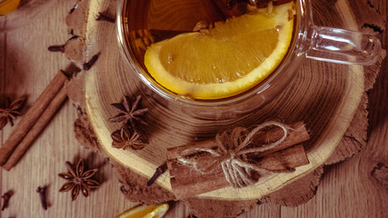Orange flavored tea with cinnamon and cardamom in glasses, orange and cinnamon sticks on a wooden table. Mulled wine and spices on wooden background. Selective focus. Close up.