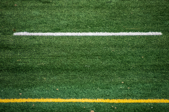 View of artificial turf and white and yellow line markings on American football field