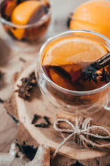 Orange flavored tea with cinnamon and cardamom in glasses, orange and cinnamon sticks on a wooden table. Mulled wine and spices on wooden background. Selective focus. Close up.