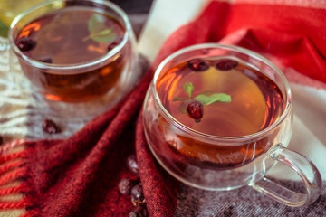 Dried rose-hip berries and rosehip tea on the rustic table. In a glass cups tea of rosehip and leaves mint. Medicinal plants and herbs composition. Autumn and winter season background. Close up