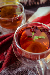 Dried rose-hip berries and rosehip tea on the rustic table. In a glass cups tea of rosehip and leaves mint. Medicinal plants and herbs composition. Autumn and winter season background. Close up