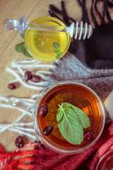Dried rose-hip berries and rosehip tea on the rustic table. In a glass cup tea of rosehip and leaves mint. Medicinal plants and herbs composition. Autumn and winter season background. Close up