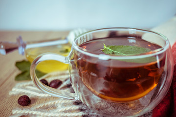 Dried rose-hip berries and rosehip tea on the rustic table. In a glass cup tea of rosehip and leaves mint. Medicinal plants and herbs composition. Autumn and winter season background. Close up