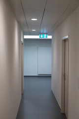 corridor with office rooms and green emergency exit sign