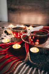 Black cup tea with dried rosehip and fresh leaves mint on the background of scattered dried rose hips and wax candles. Selective focus. Close up. Autumn and winter background.