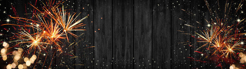 Silvester background banner panorama long- sparklers, firework and bokeh lights on rustic wooden...