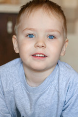 Close up portrait of cute caucasian baby boy with ginger red hair and bright blue eyes. Smiling child, happy healthy childhood concept. Indoors, copy space.