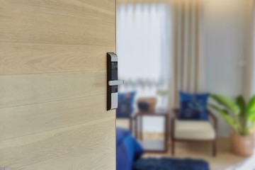 Digital Door handle or Electronics knob  for access to room security, Door wooden half opening through interior living room background, selective focus.