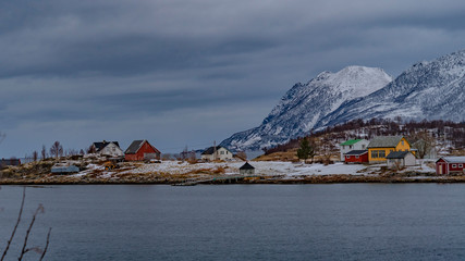 village aux maisons rouges sur une colline au bord d'un fjord norvégien enneigé et montagnes au...
