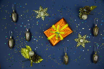 Gift tied with a ribbon snowflakes cones sequins gold color on a blue background. Christmas, Toys, New year, decorations