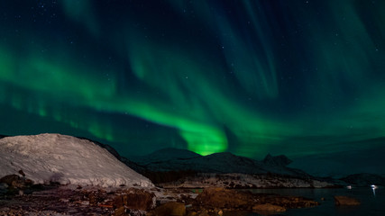 Fototapeta na wymiar aurores boréales au bord d'un fjord tranquille gelé en norvège