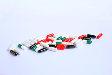 Colored capsules scattered on white paper. Close-up on a light background. 