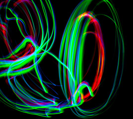 The chaotic blurred lines of color lights on dark background. Colorful lights blurred by motion. Green and Red colors.