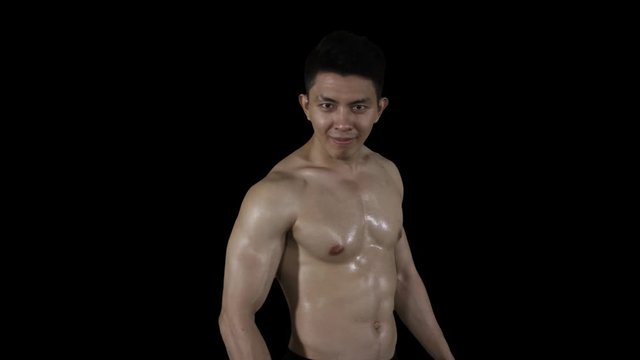 Slow motion of handsome muscular man showing thumb up at the camera in the studio with dark background