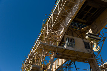Fototapeta na wymiar Bottom view of a large specialized dam crane against a clear blue sky. The old crane is in perfect condition to ensure safety on the dam