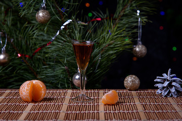Fototapeta na wymiar A glass of cognac with tangerines on the surface of the table against the background of the Christmas tree.