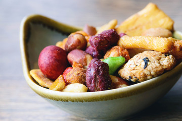 Nuts and cookies seasoned with salt and spices in a small plate on a wooden table. Great beer snack. Spicy snacks.