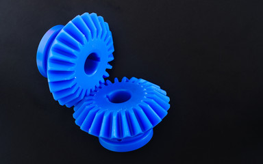 Blue Bevel Gears made of plastic on a black background.