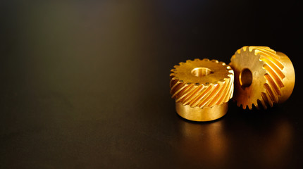 Helical Gears Brass on a black background , concept of work process movement gears