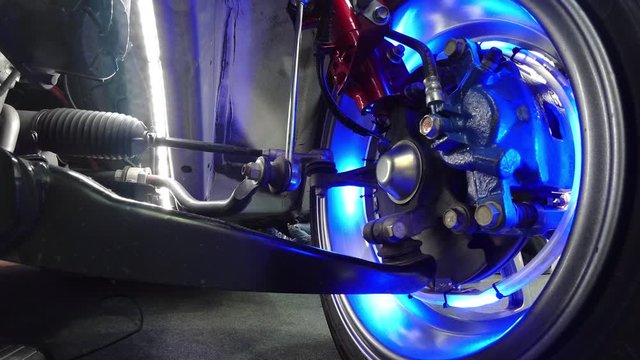 Car suspension from the inside. Multi-colored lights and highlights create a sense of circular rotation. System of tires, shock absorbers and linkages that connects a vehicle to its wheels. Timelapse.