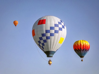 Colorful hot air balloons in flight over a field