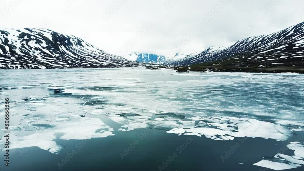 Wall mural frozen lake with pieces of ice floating at the surface, cold mountain landscape with snow in arctic 