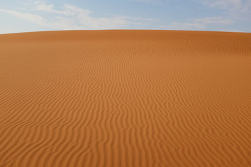 Desert sand ripples under a blue sky