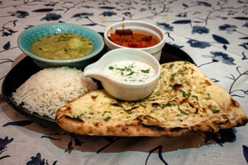 North indian home made thali with rice and nan bread served with curry and curd