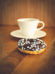 Chocolate donuts sprinkled with colorful stars on the table. Coffee decorations in the background. Donut on table. Chocolate donut at sunrise. Coffee and donut.