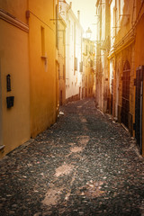 Sun shining over a narrow alley in old town Alghero