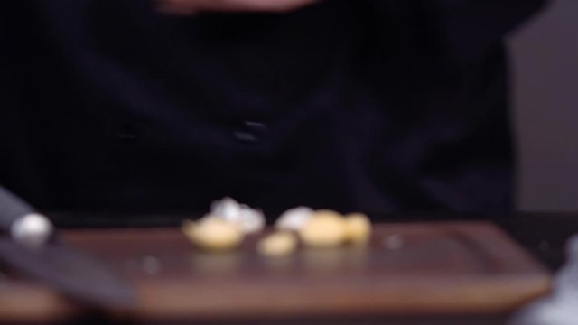 Step by step. Dicing organic garlic on wood cutting board.