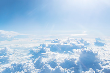 View from the airplane window on clouds, blue clear sky. Look seen through window of an aircraft. Good sunny weather. High view from above to clouds. Heaven concept. Sky background.