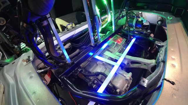 Motor-generator in electric car. Wires, metal structures, mounts. Running lights of bright LED illumination. The concept of charging a modern electric vehicle and artificial intelligence.
