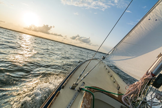 Sailing Boat Sailing Fast Into The Sunset On Choppy Sea With Tilted Horizon