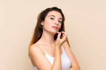 Young brunette girl holding red lipstick over isolated background