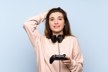 Young brunette girl over isolated blue background playing at videogames