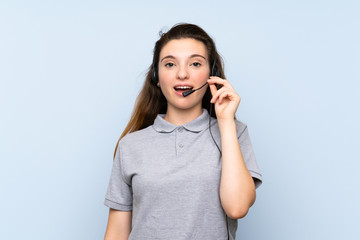 Fototapeta premium Young brunette girl over isolated blue background working with headset