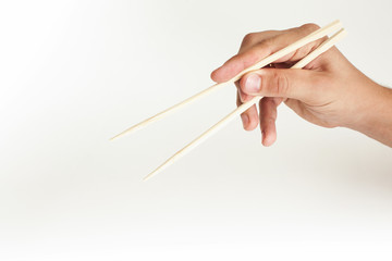 Hand on a white background holds sushi sticks