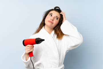 Young woman in a bathrobe with hair hairdryer having doubts and with confuse face expression