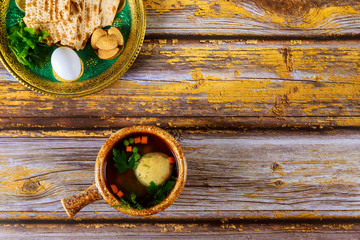 Traditional Jewish matzo ball soup and seder plate on wooden table.